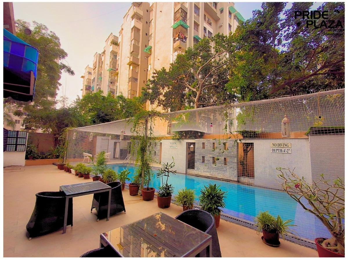 a courtyard with a swimming pool with potted plants at Pride Plaza Hotel, Ahmedabad in Ahmedabad
