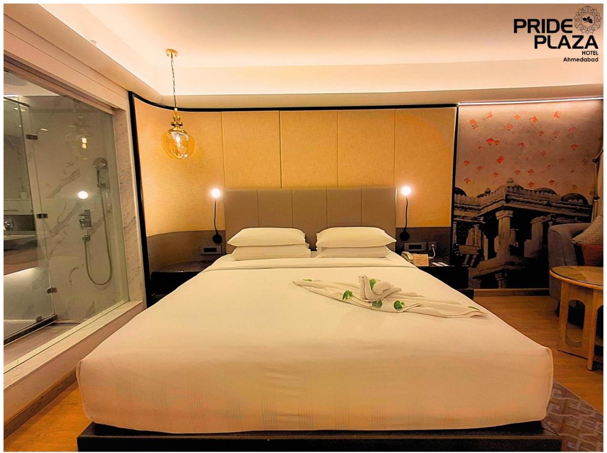 a bedroom with a large white bed and a shower at Pride Plaza Hotel, Ahmedabad in Ahmedabad