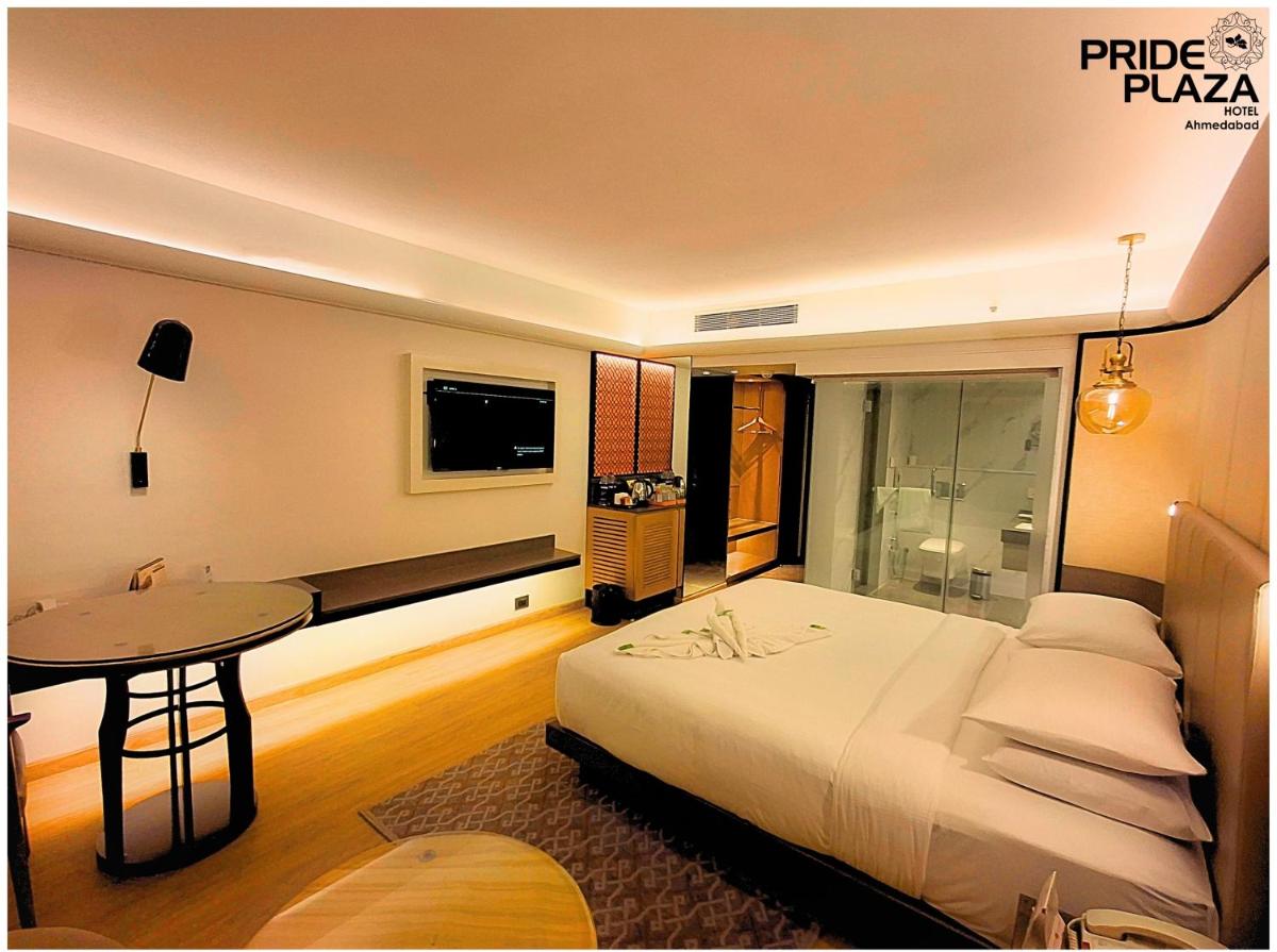 a bedroom with a bed and a table and a television at Pride Plaza Hotel, Ahmedabad in Ahmedabad