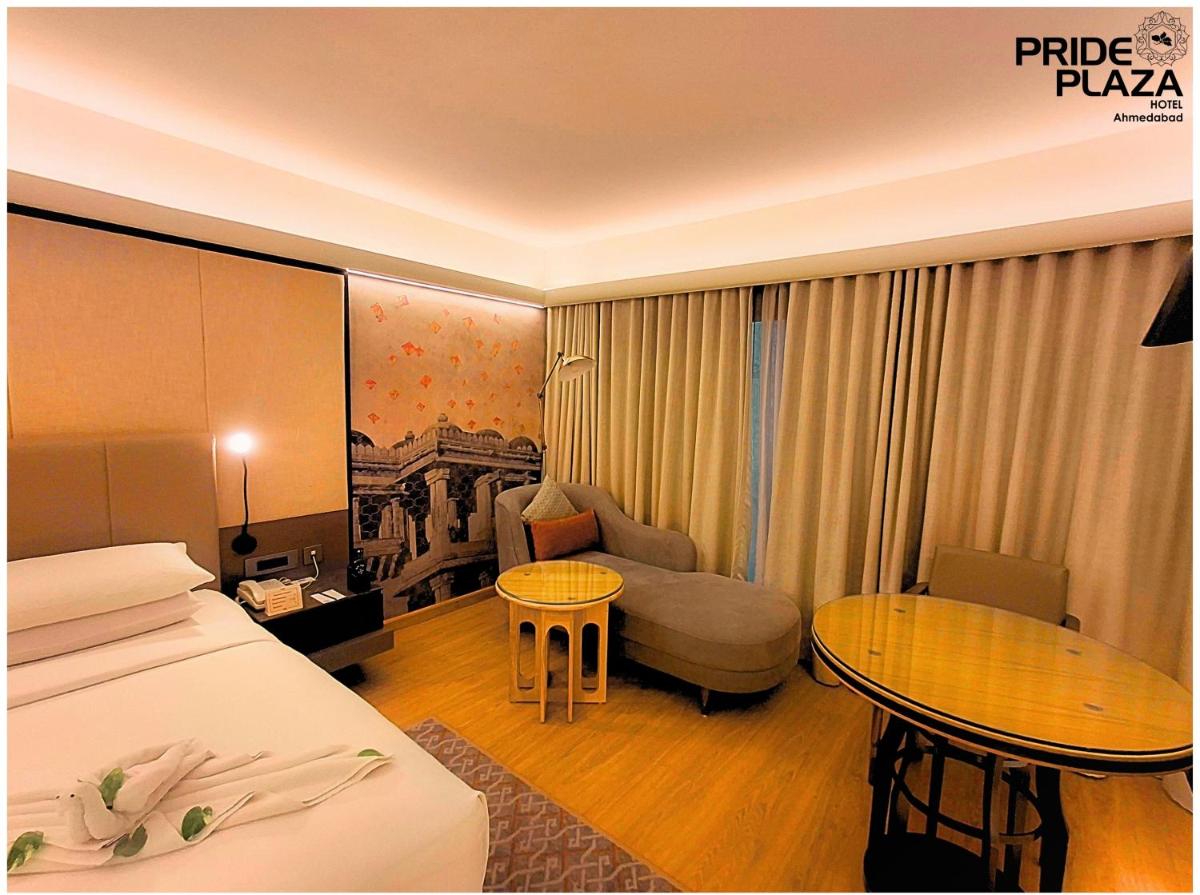 a hotel room with a bed and a couch and a table at Pride Plaza Hotel, Ahmedabad in Ahmedabad