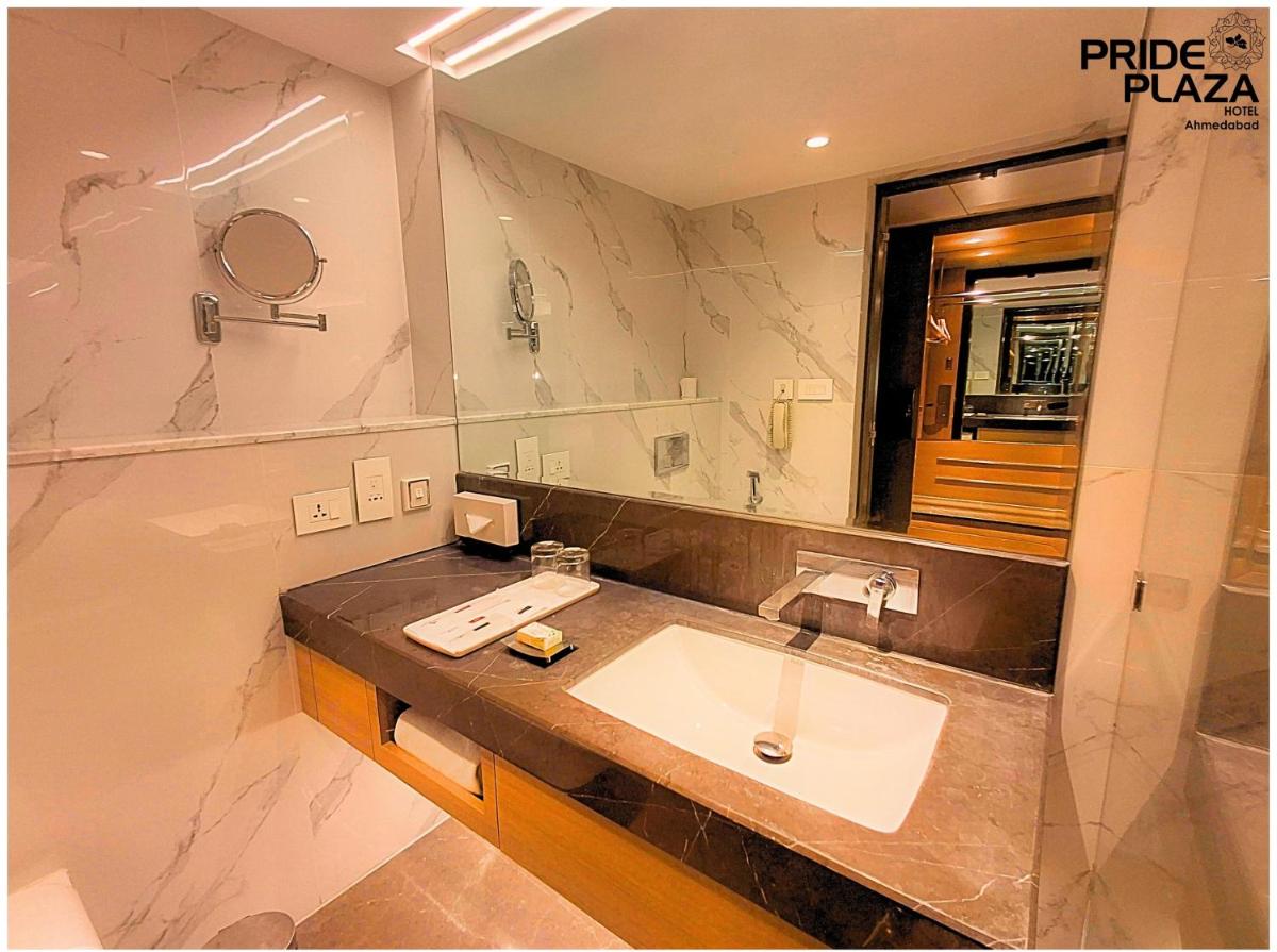 a bathroom with a sink and a large mirror at Pride Plaza Hotel, Ahmedabad in Ahmedabad