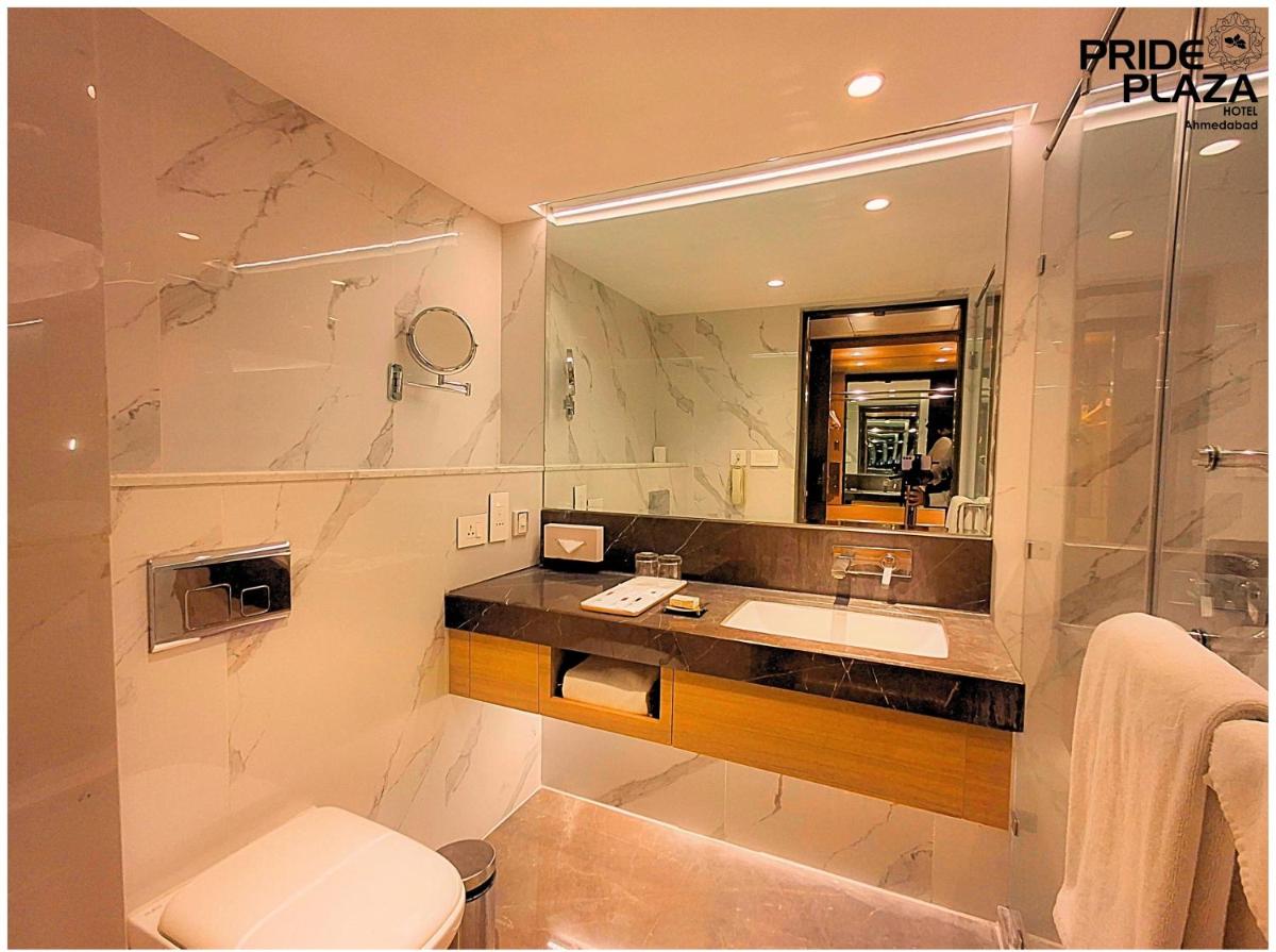 a bathroom with a sink and a toilet and a mirror at Pride Plaza Hotel, Ahmedabad in Ahmedabad