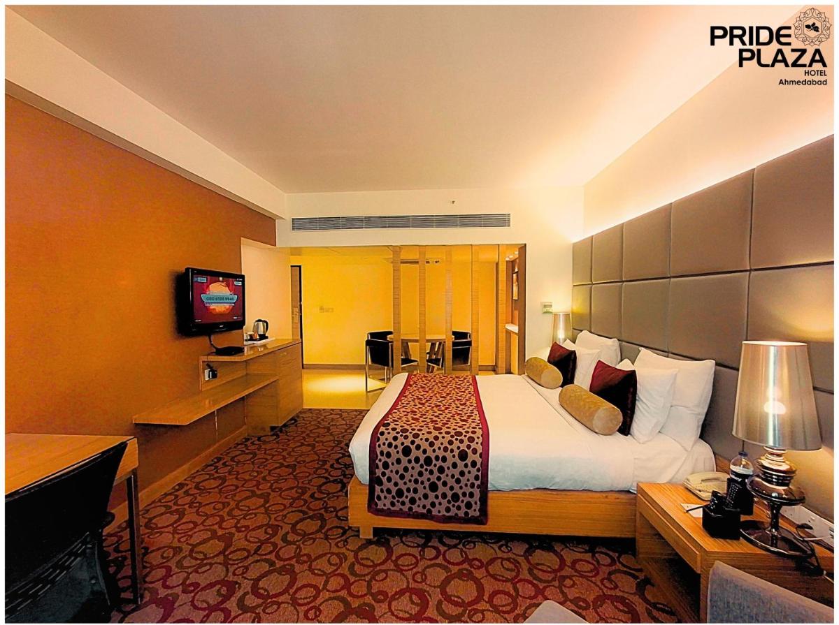 a hotel room with a large bed and a television at Pride Plaza Hotel, Ahmedabad in Ahmedabad
