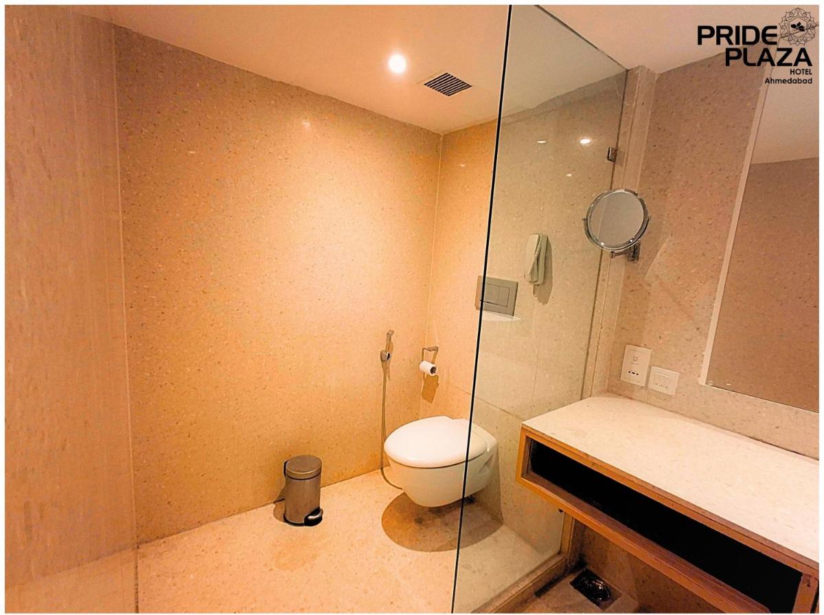 a bathroom with a toilet and a glass shower at Pride Plaza Hotel, Ahmedabad in Ahmedabad