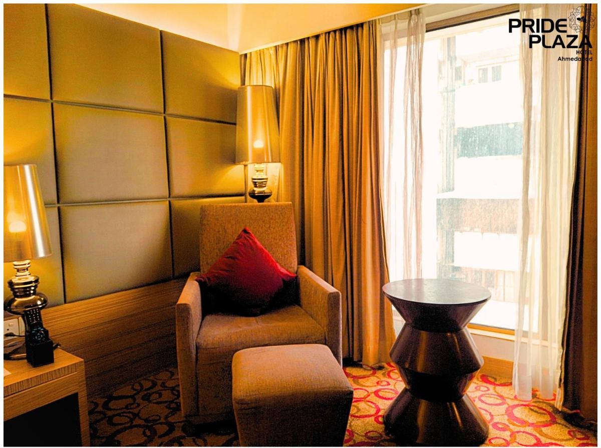 a hotel room with a chair and a window at Pride Plaza Hotel, Ahmedabad in Ahmedabad