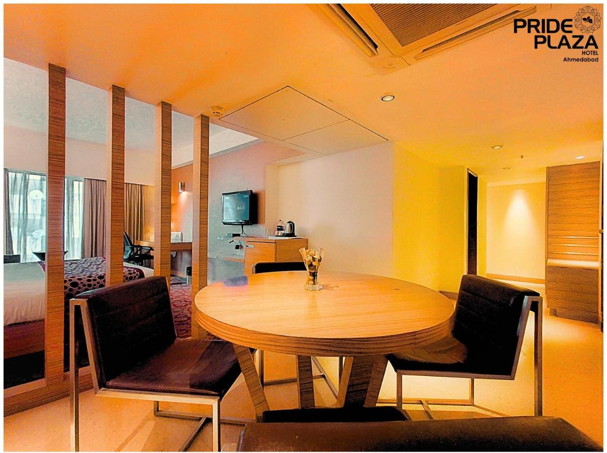 a dining room with a wooden table and chairs at Pride Plaza Hotel, Ahmedabad in Ahmedabad