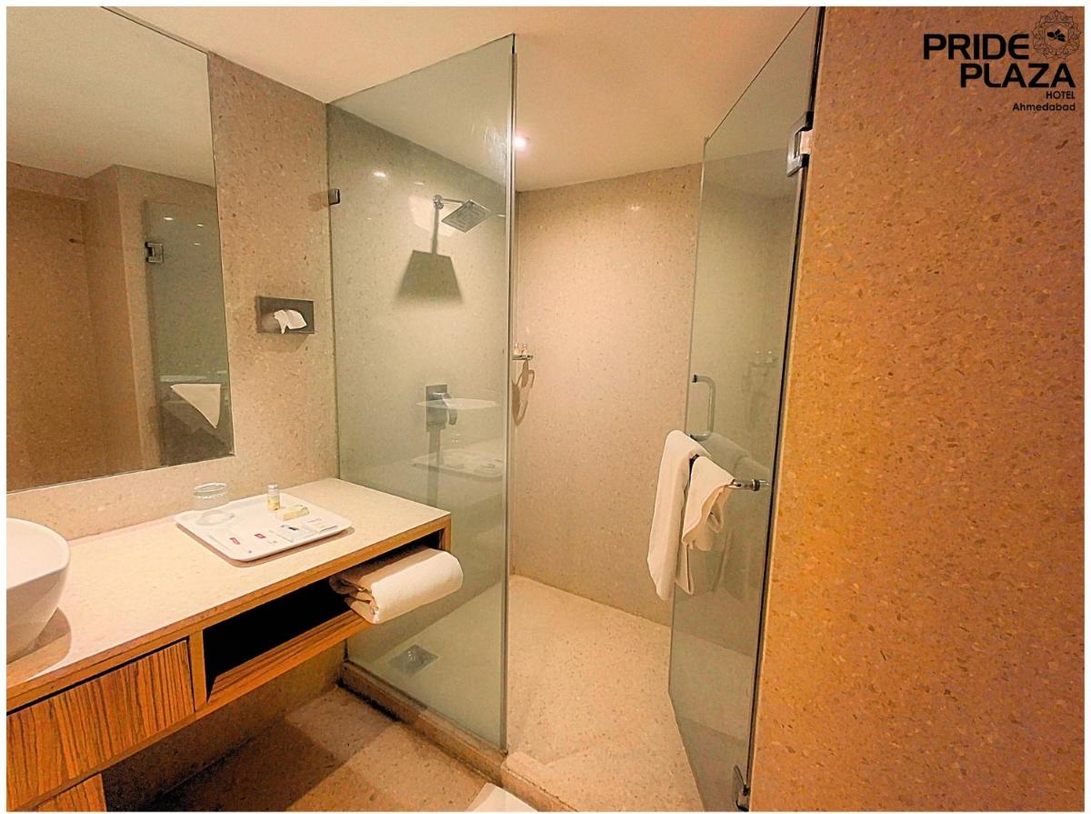 a bathroom with a glass shower and a sink at Pride Plaza Hotel, Ahmedabad in Ahmedabad