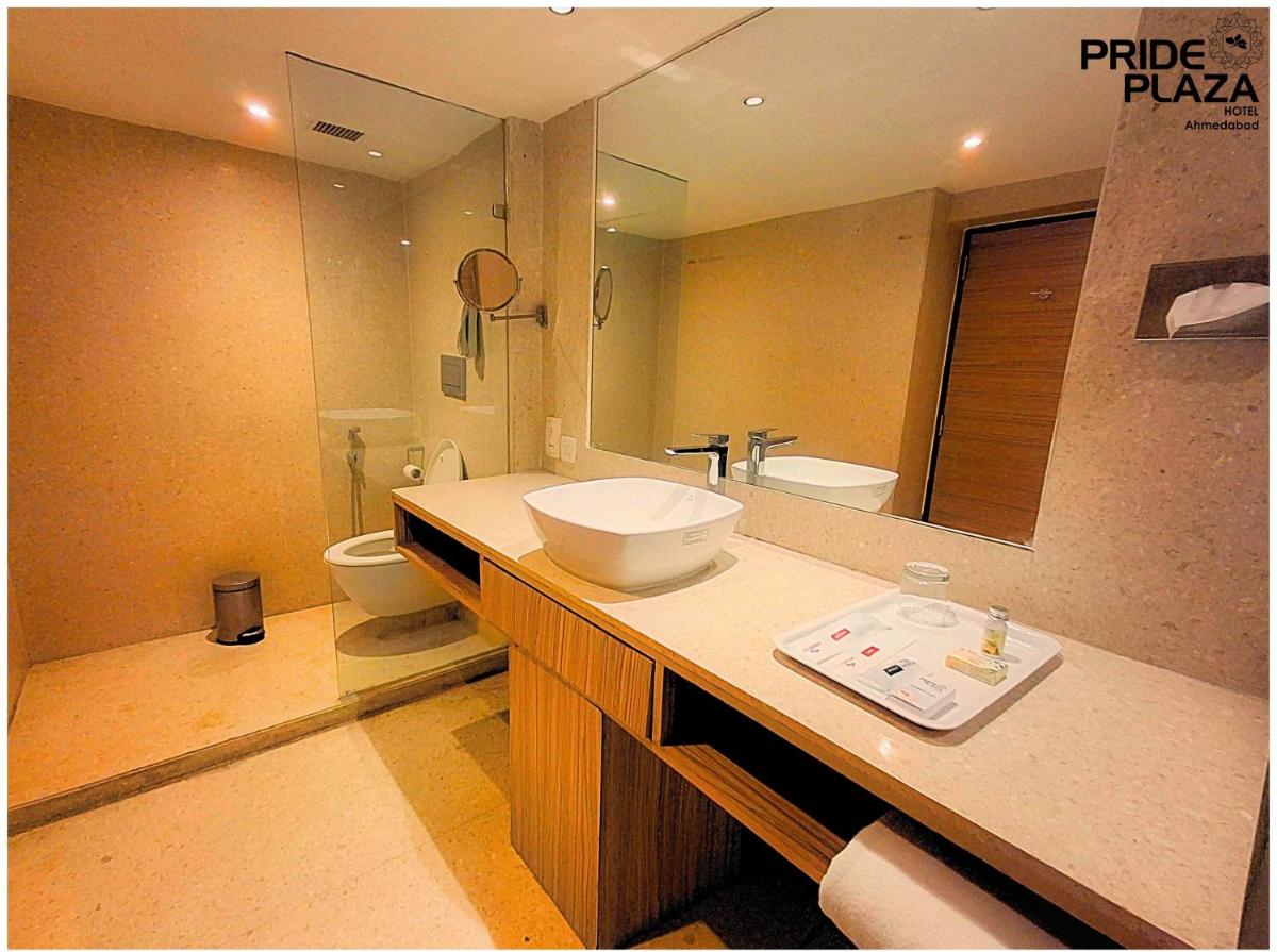 a bathroom with a sink and a toilet and a mirror at Pride Plaza Hotel, Ahmedabad in Ahmedabad