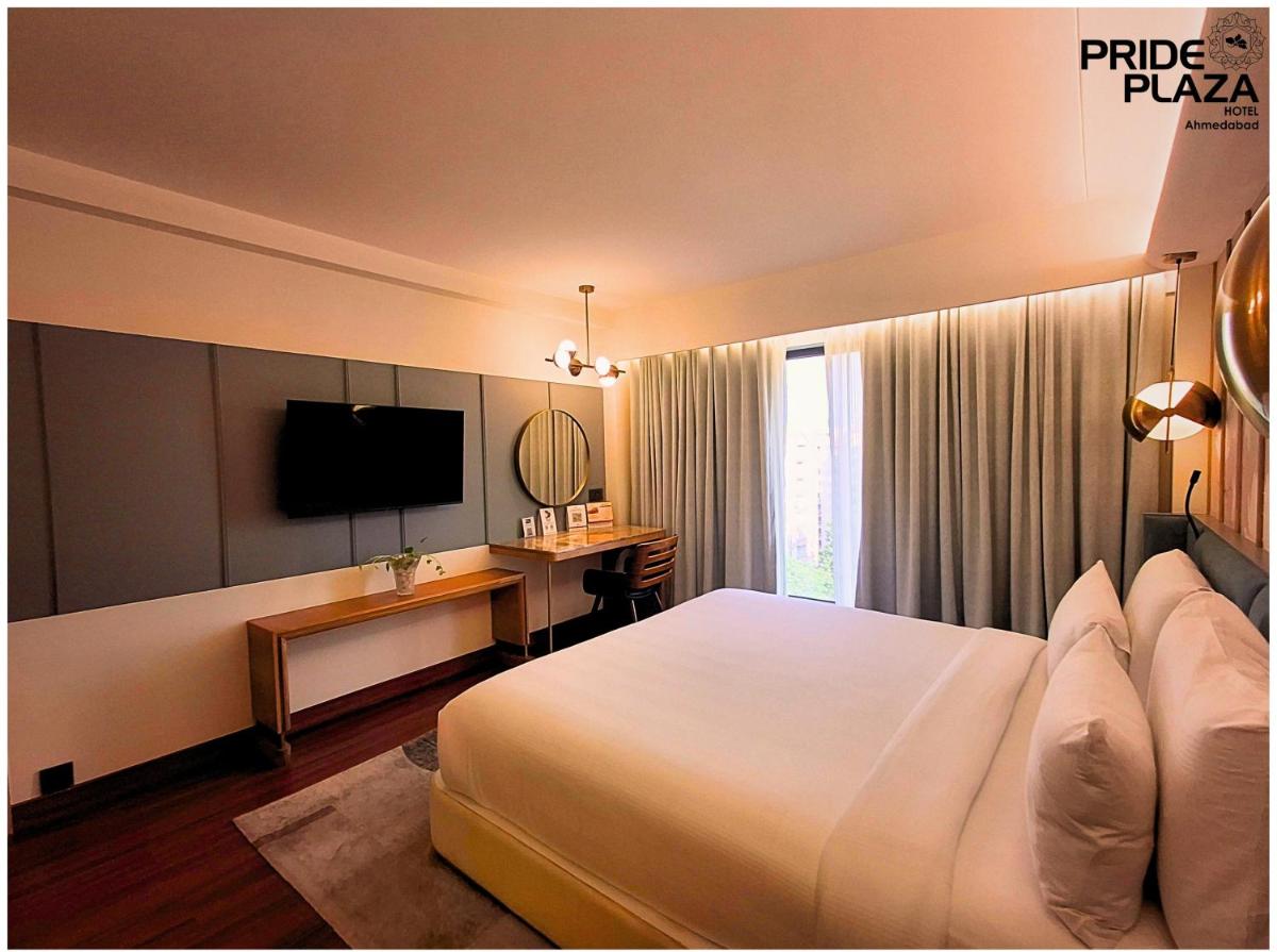 a hotel room with a large bed and a television at Pride Plaza Hotel, Ahmedabad in Ahmedabad