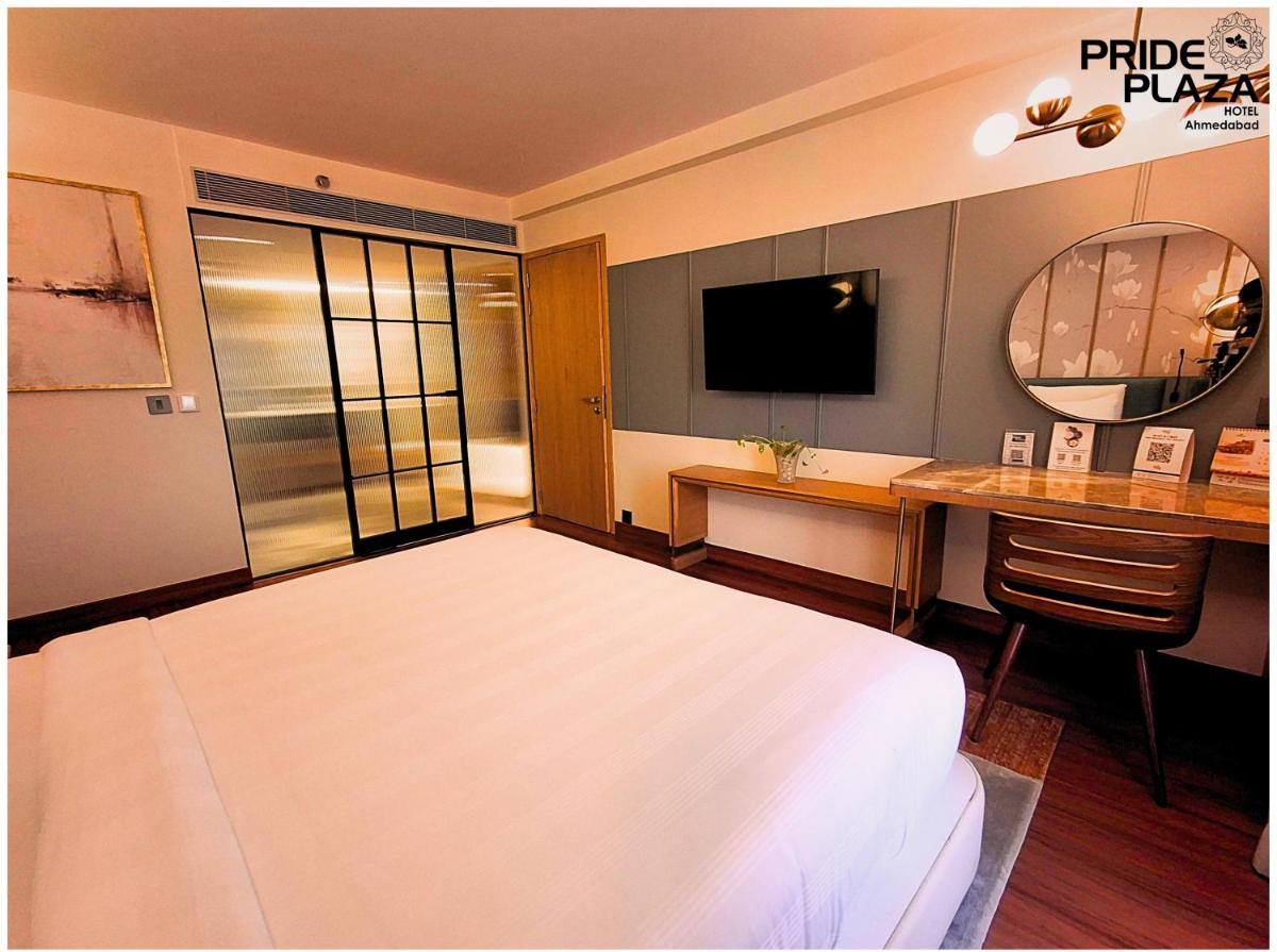 a hotel room with a bed and a desk and a television at Pride Plaza Hotel, Ahmedabad in Ahmedabad