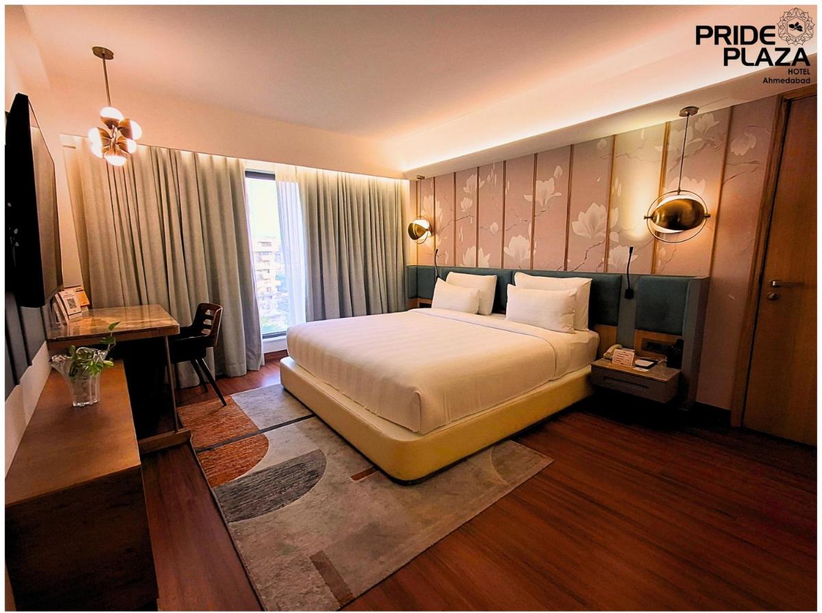 a hotel room with a bed and a desk and a bed sidx sidx sidx at Pride Plaza Hotel, Ahmedabad in Ahmedabad