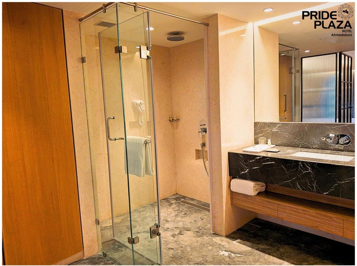 a bathroom with a glass shower and a sink at Pride Plaza Hotel, Ahmedabad in Ahmedabad