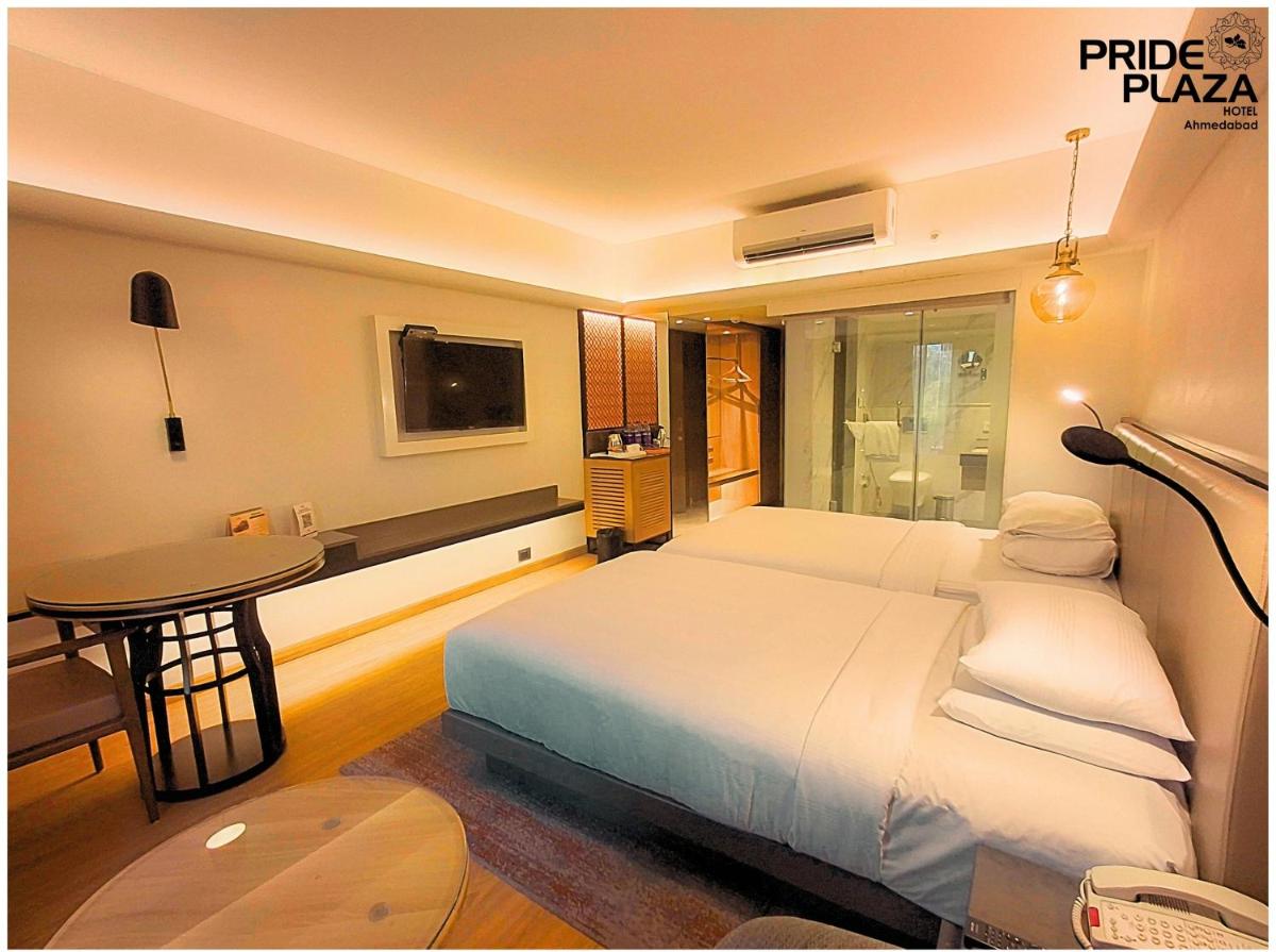 a bedroom with a bed and a table and a television at Pride Plaza Hotel, Ahmedabad in Ahmedabad