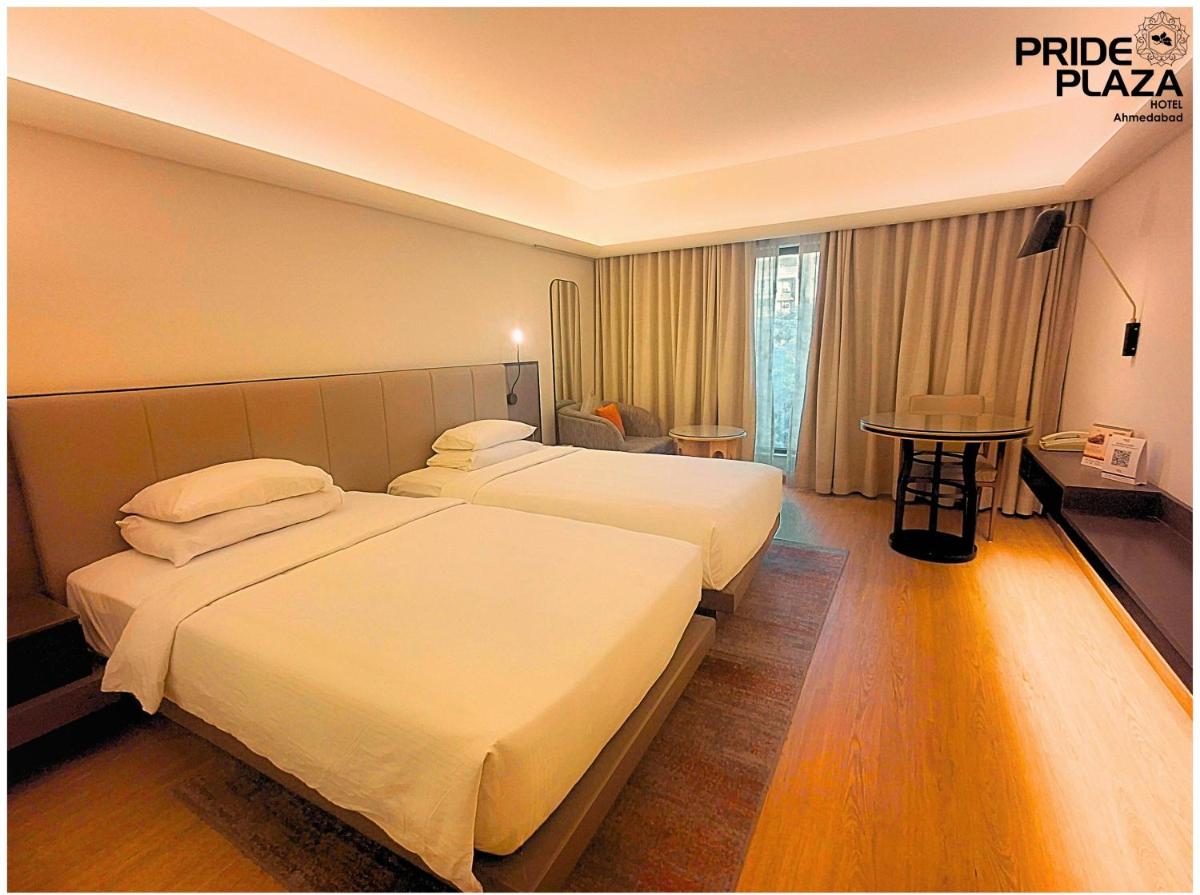 a hotel room with two beds and a table at Pride Plaza Hotel, Ahmedabad in Ahmedabad