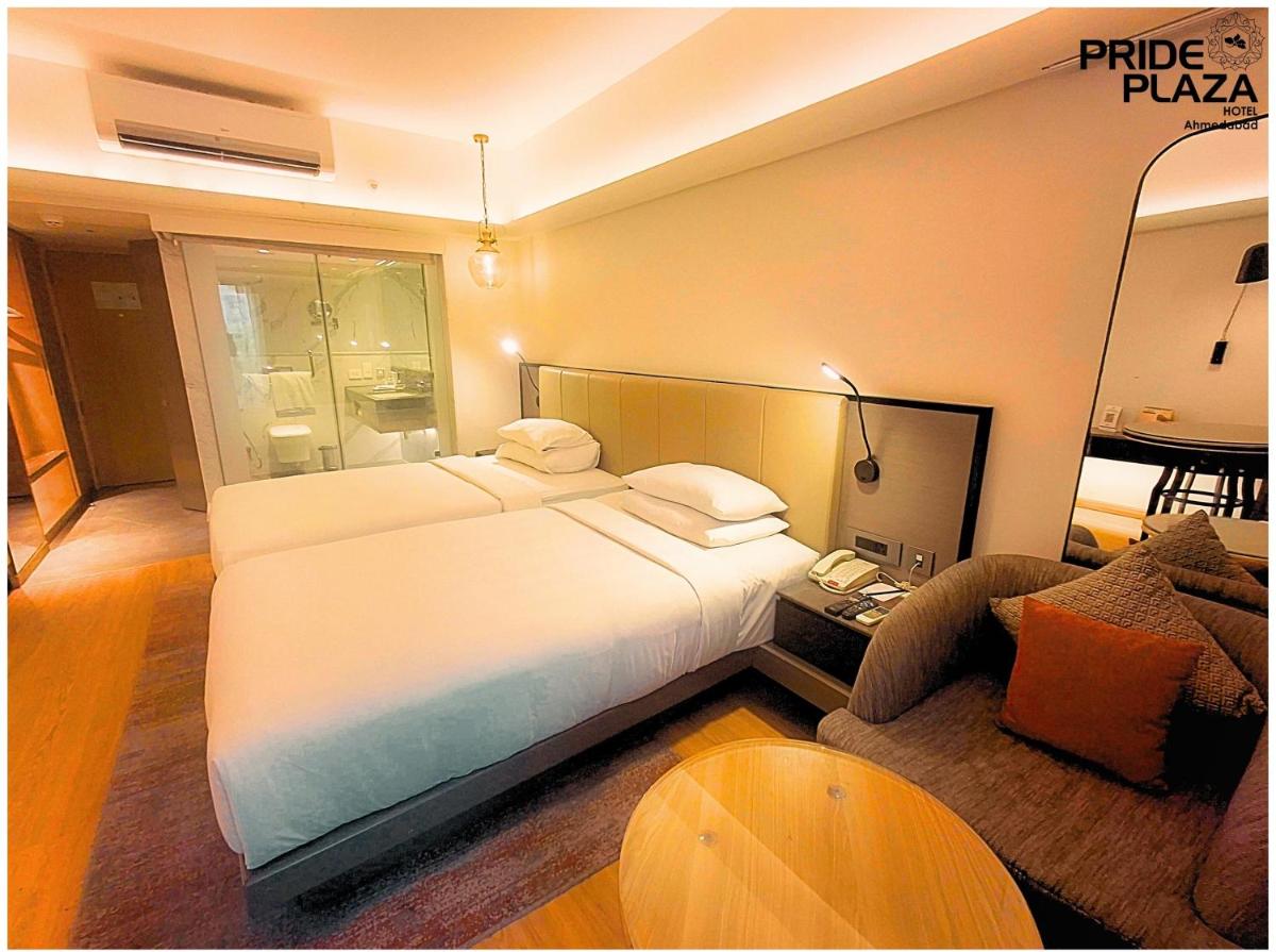a hotel room with a large bed and a table at Pride Plaza Hotel, Ahmedabad in Ahmedabad
