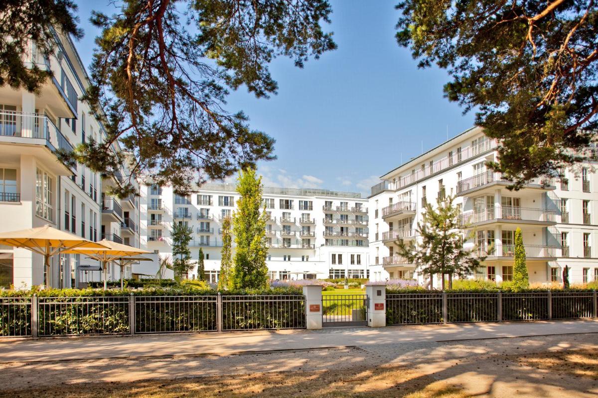 ein Mehrfamilienhaus mit Zaun und Bäumen in der Unterkunft Steigenberger Grandhotel & Spa Heringsdorf in Heringsdorf