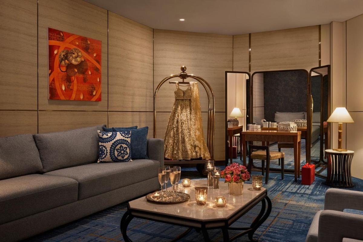 a living room with a couch and a dress hanging on a wall at JW Marriott Mumbai Juhu in Mumbai