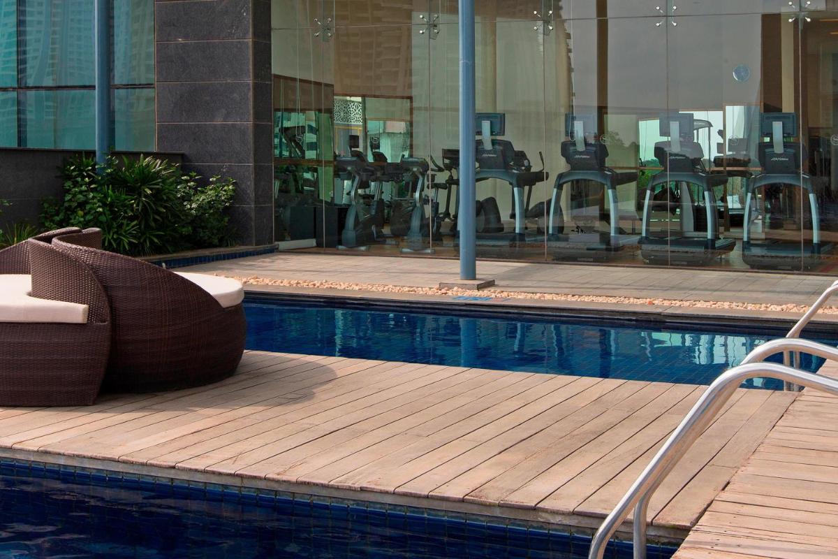 a pool with chairs and tables in a building at Sheraton Grand Bangalore Hotel at Brigade Gateway in Bengaluru