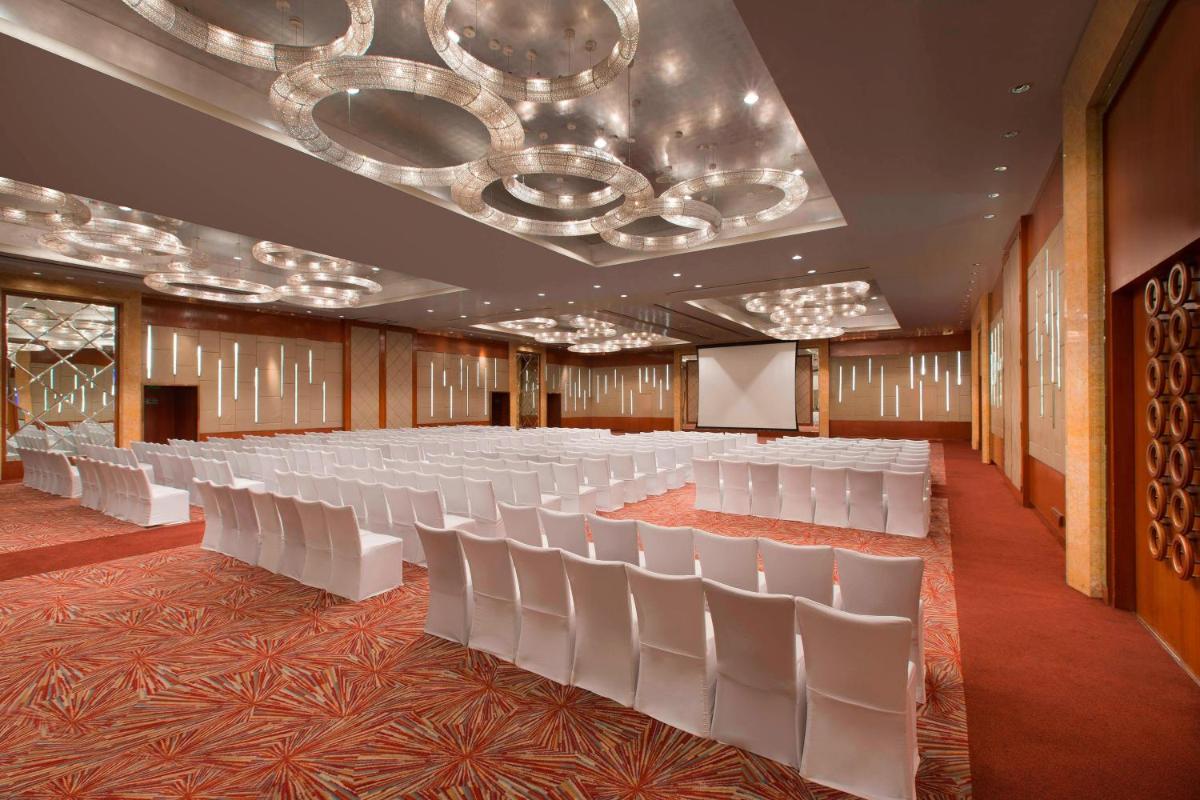 a conference room with white chairs and a chandelier at Sheraton Grand Bangalore Hotel at Brigade Gateway in Bengaluru