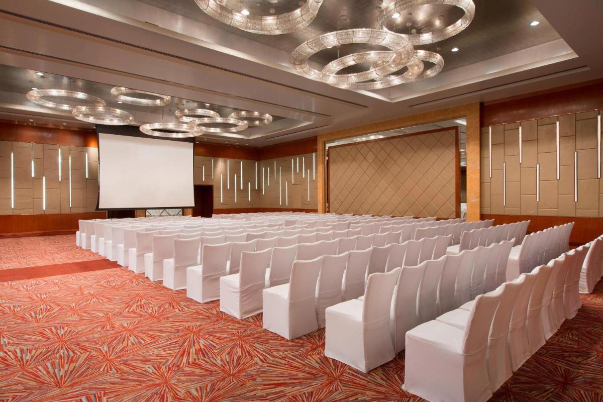 a conference room with white chairs and a screen at Sheraton Grand Bangalore Hotel at Brigade Gateway in Bengaluru