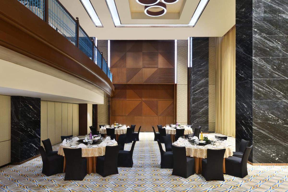 a dining room with tables and chairs and a staircase at Sheraton Grand Bangalore Hotel at Brigade Gateway in Bengaluru