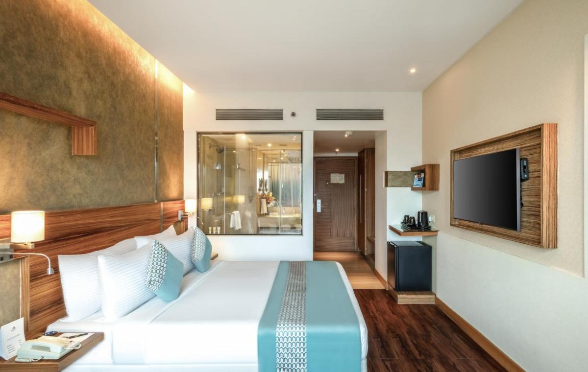 a hotel room with a bed and a flat screen tv at Sayaji Pune in Pune