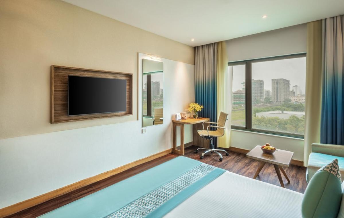 a hotel room with a bed and a tv at Sayaji Pune in Pune