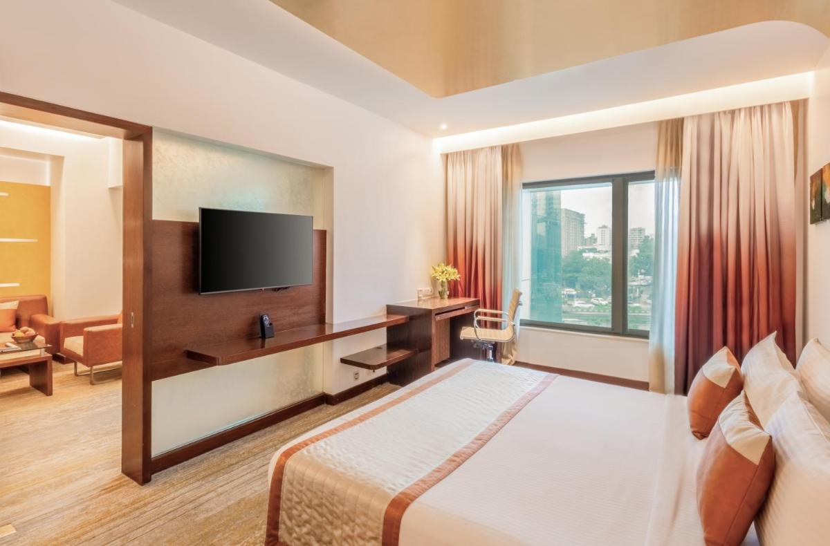 a hotel room with a bed and a flat screen tv at Sayaji Pune in Pune