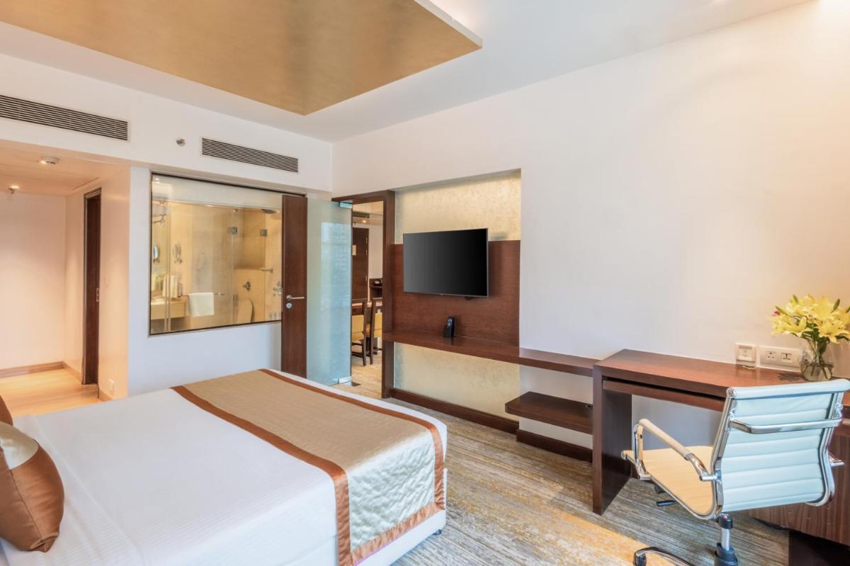 a hotel room with a bed a desk and a computer at Sayaji Pune in Pune