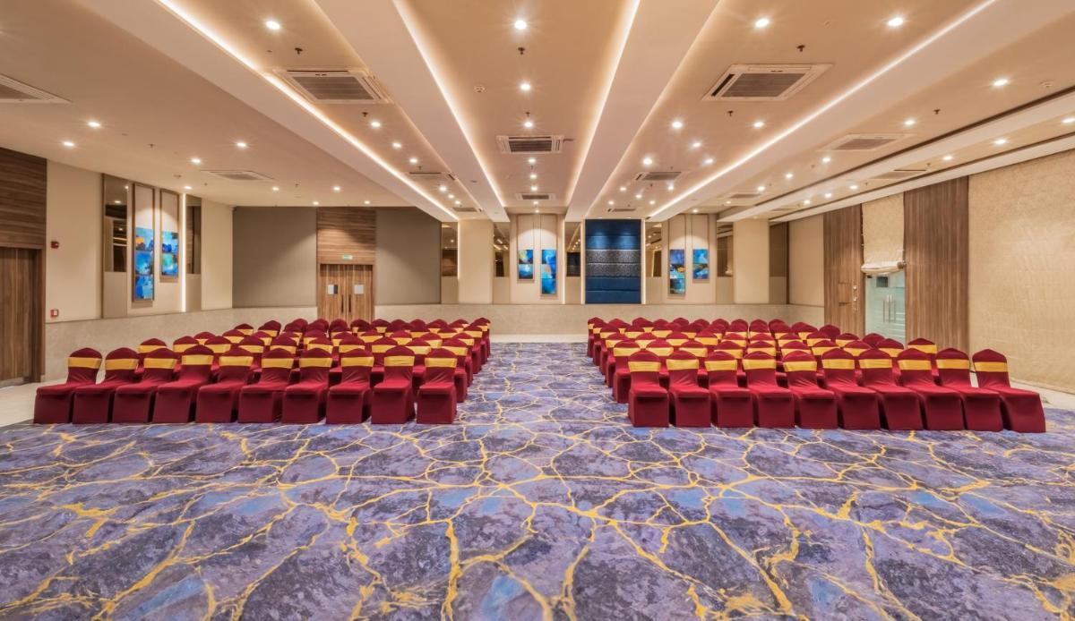 an empty auditorium with red chairs in a large room at Sayaji Pune in Pune