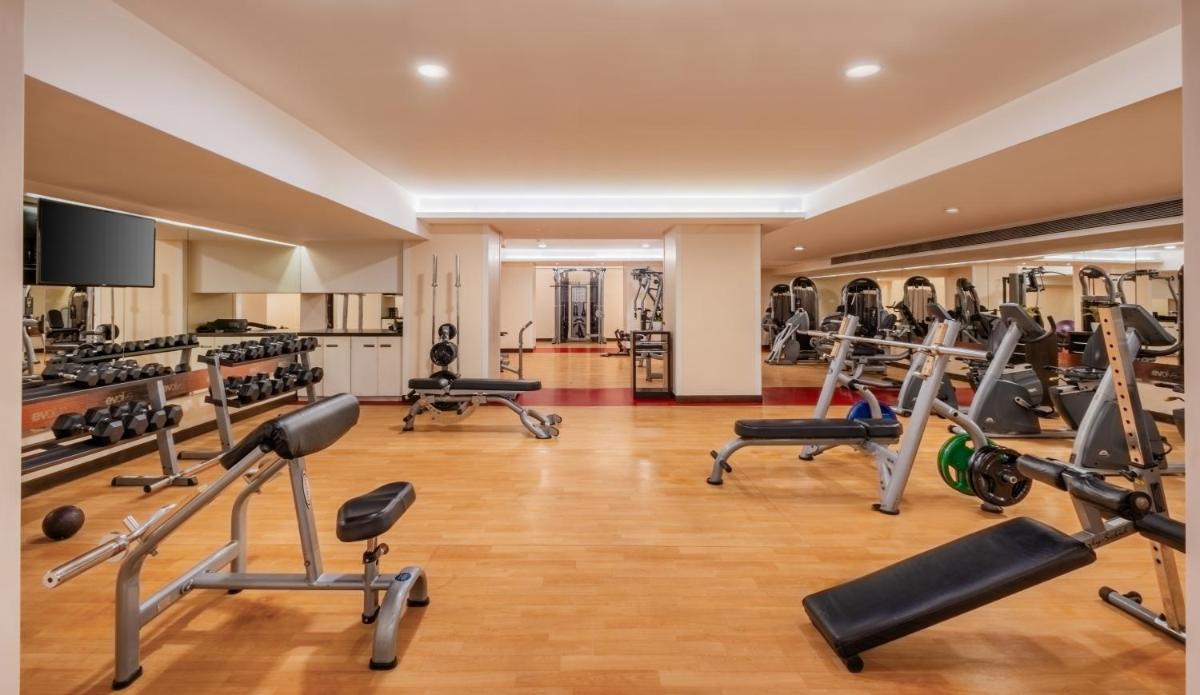a gym with several treadmills and machines in a room at Sayaji Pune in Pune