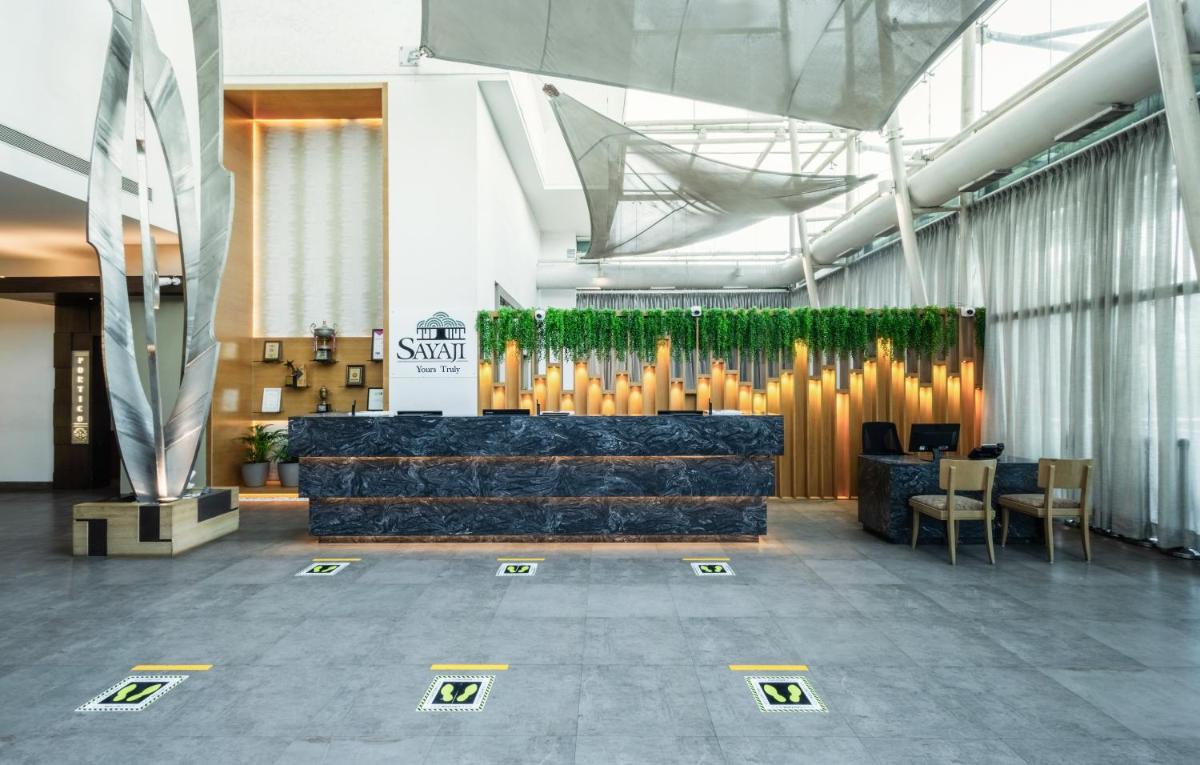 a lobby with a bench and chairs in a building at Sayaji Pune in Pune