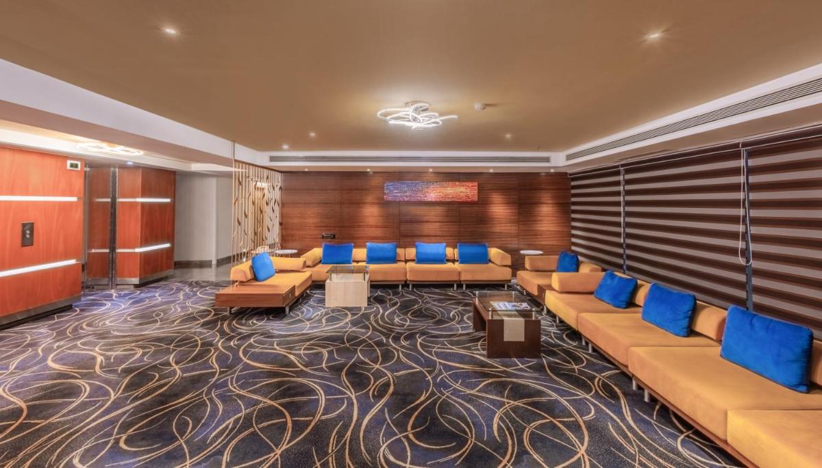 a conference room with couches and chairs on a carpet at Sayaji Pune in Pune