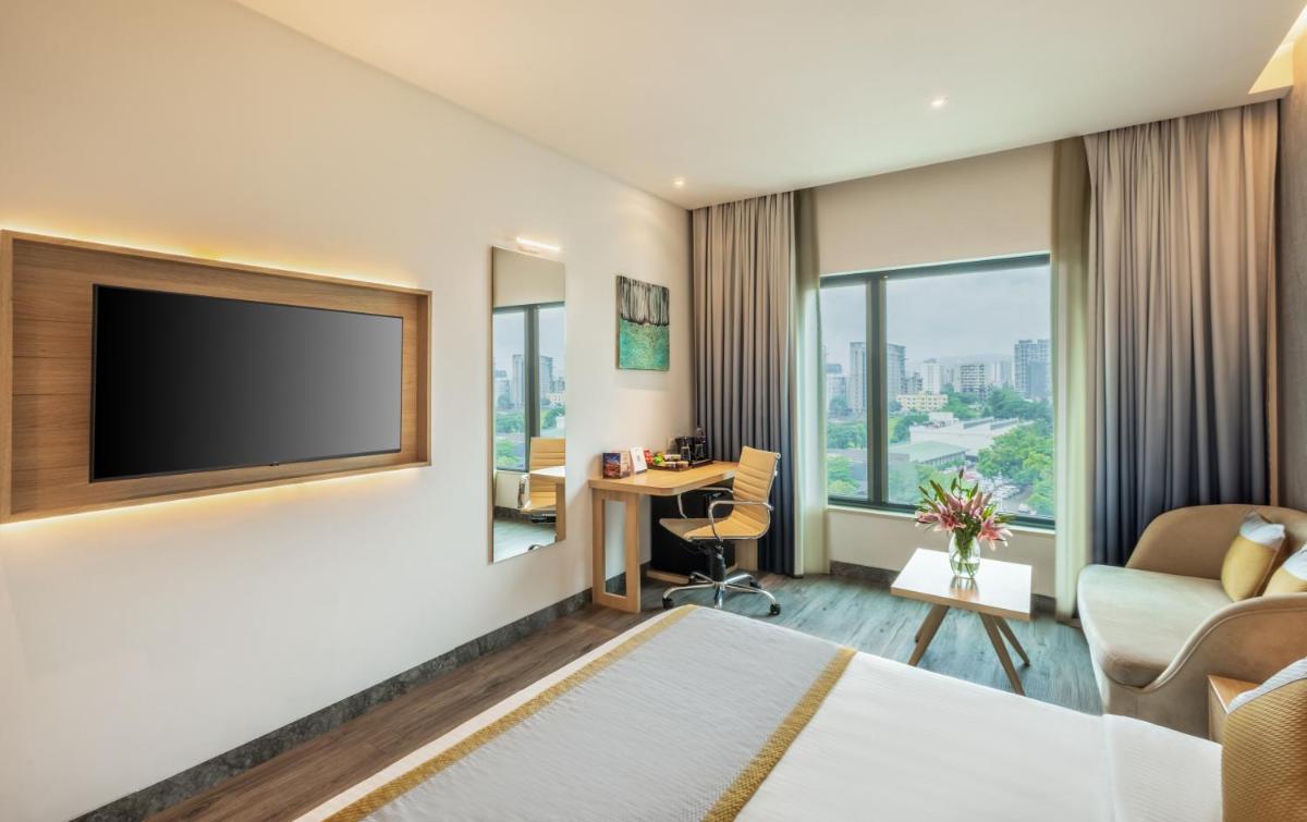 a hotel room with a bed and a flat screen tv at Sayaji Pune in Pune