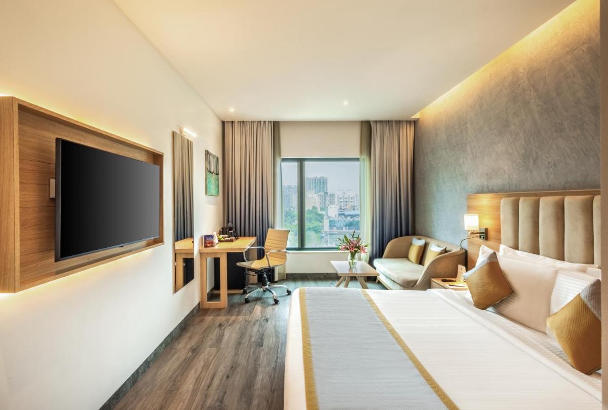 a hotel room with a bed and a flat screen tv at Sayaji Pune in Pune