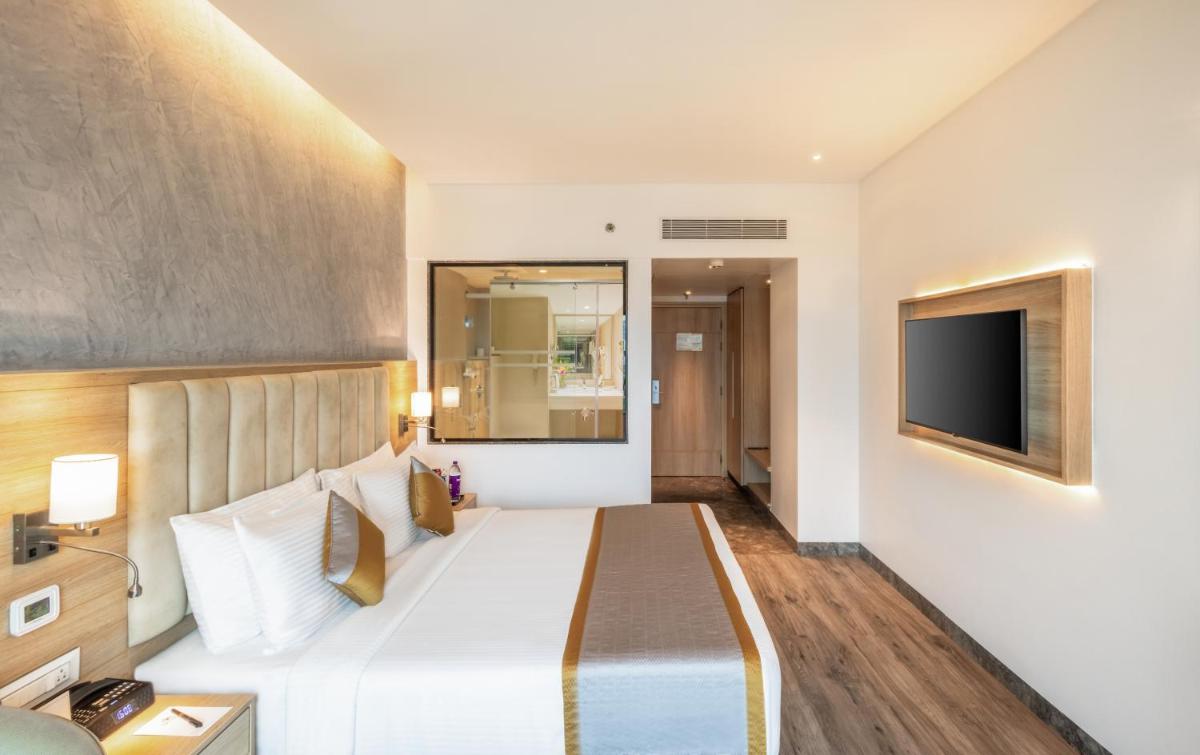 a hotel room with a large bed and a television at Sayaji Pune in Pune