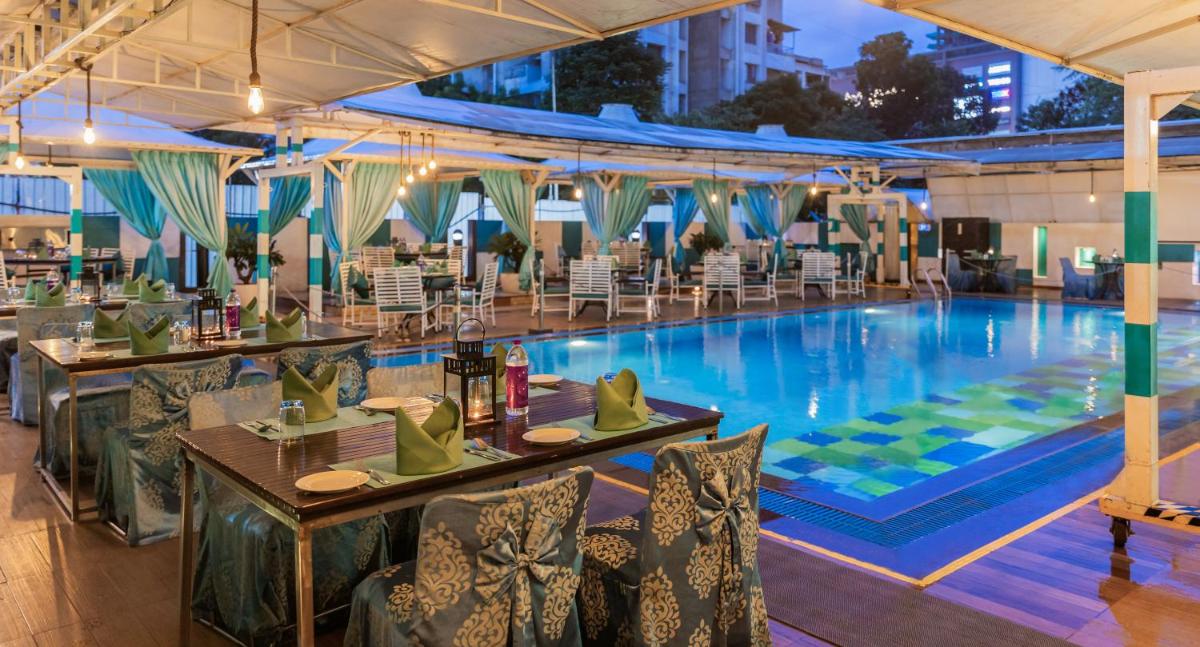 a large swimming pool with tables and chairs next to it at Sayaji Pune in Pune