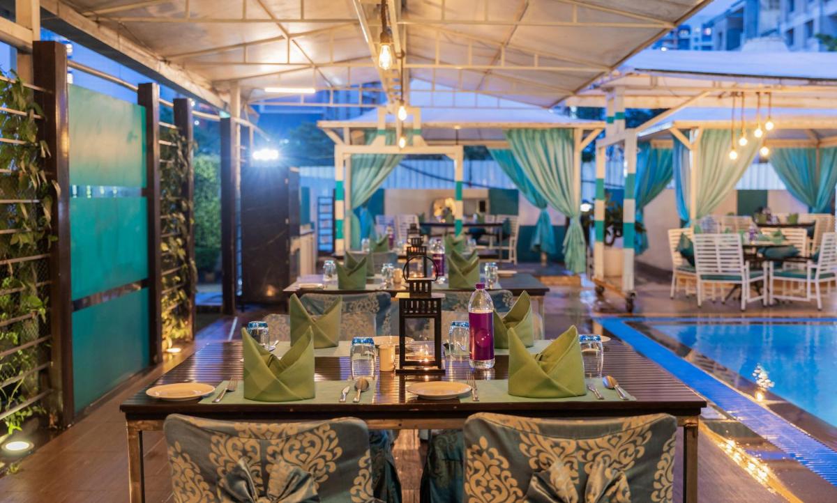 a restaurant with a pool and a table with wine bottles at Sayaji Pune in Pune