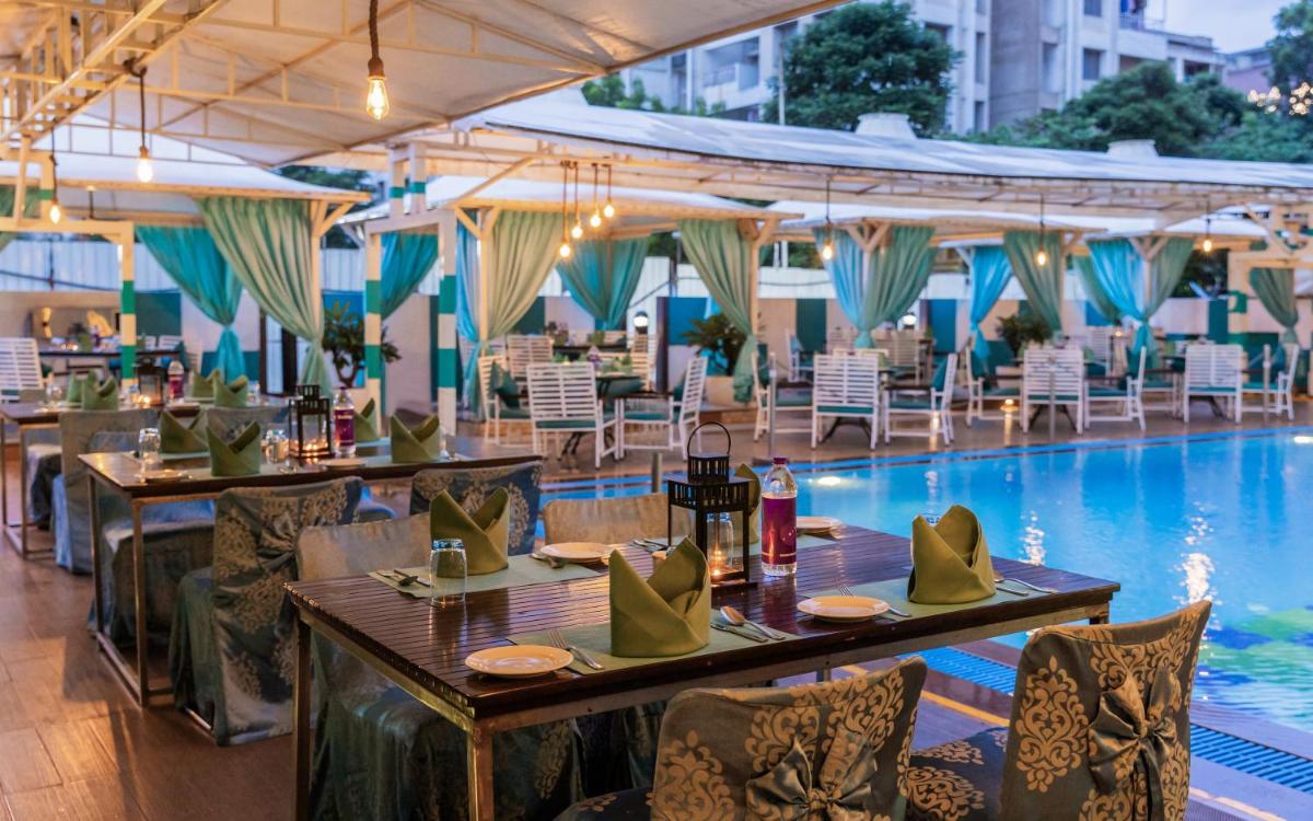 a restaurant with a pool and tables and chairs at Sayaji Pune in Pune