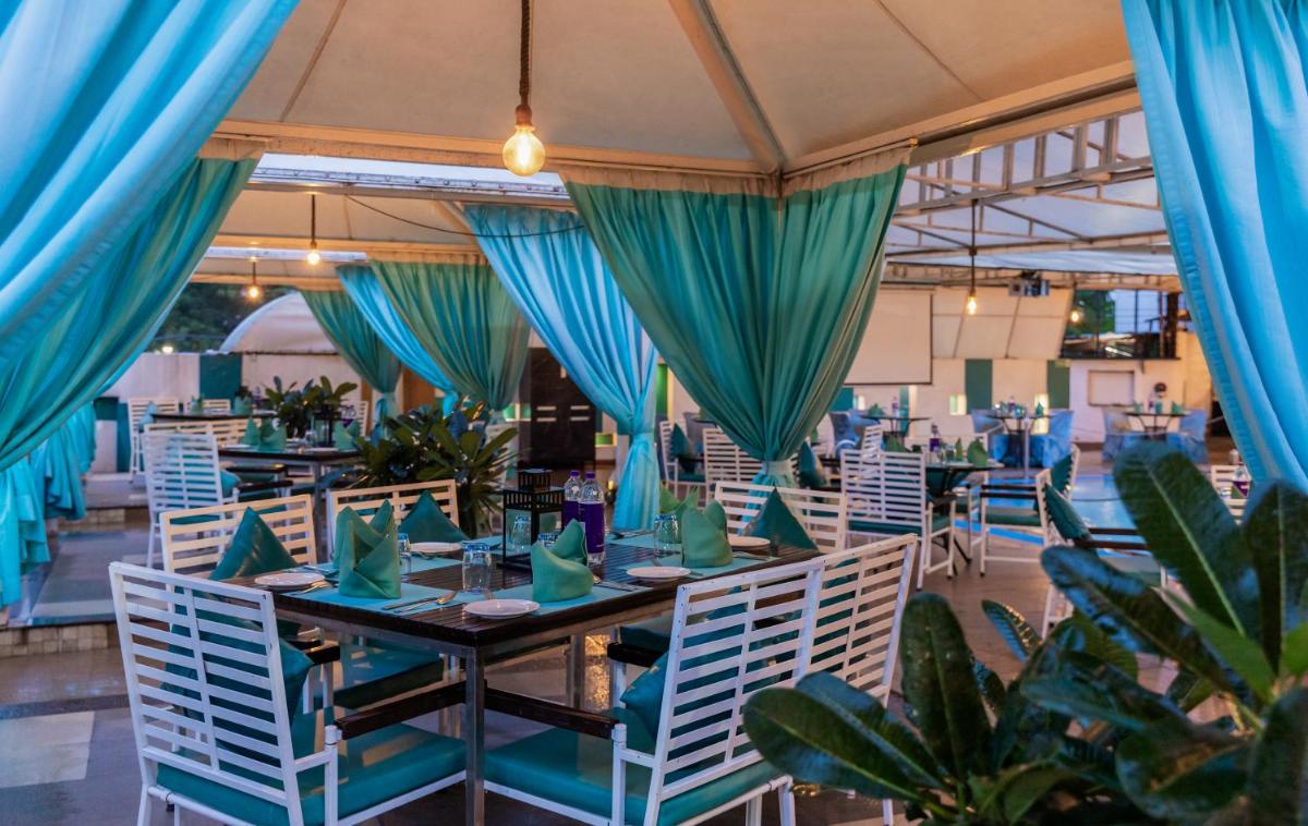 a dining room with blue drapes and tables and chairs at Sayaji Pune in Pune
