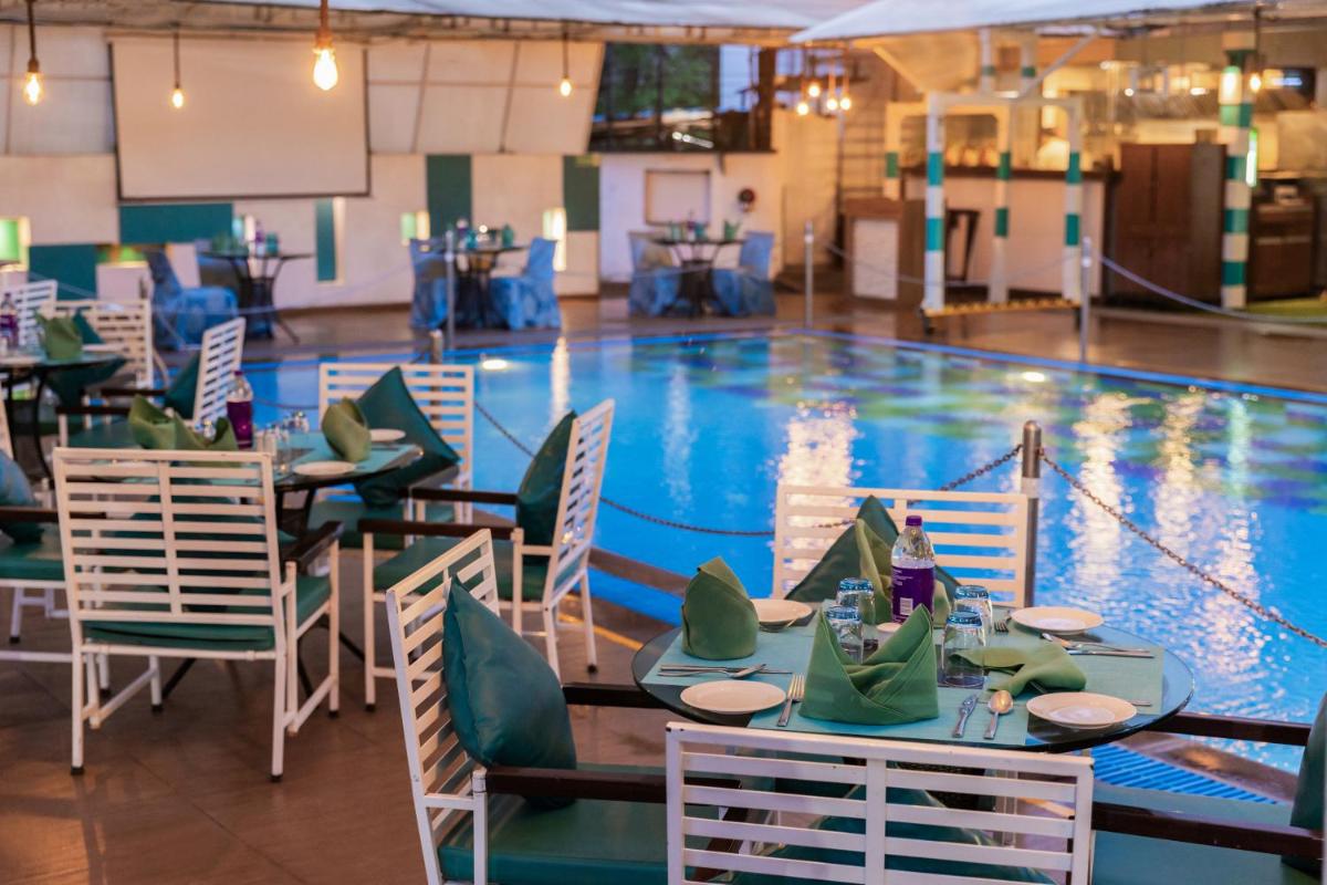 a pool with tables and chairs in front of a swimming pool at Sayaji Pune in Pune