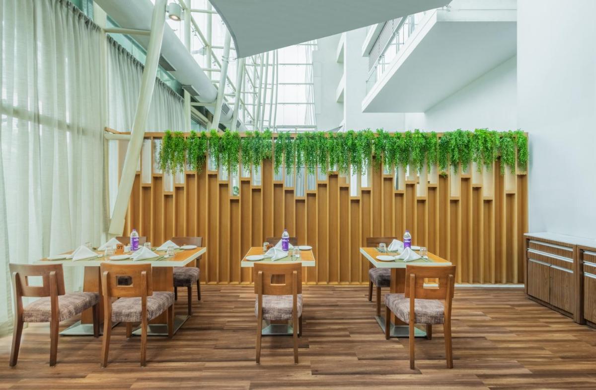 a dining room with tables and chairs and plants at Sayaji Pune in Pune