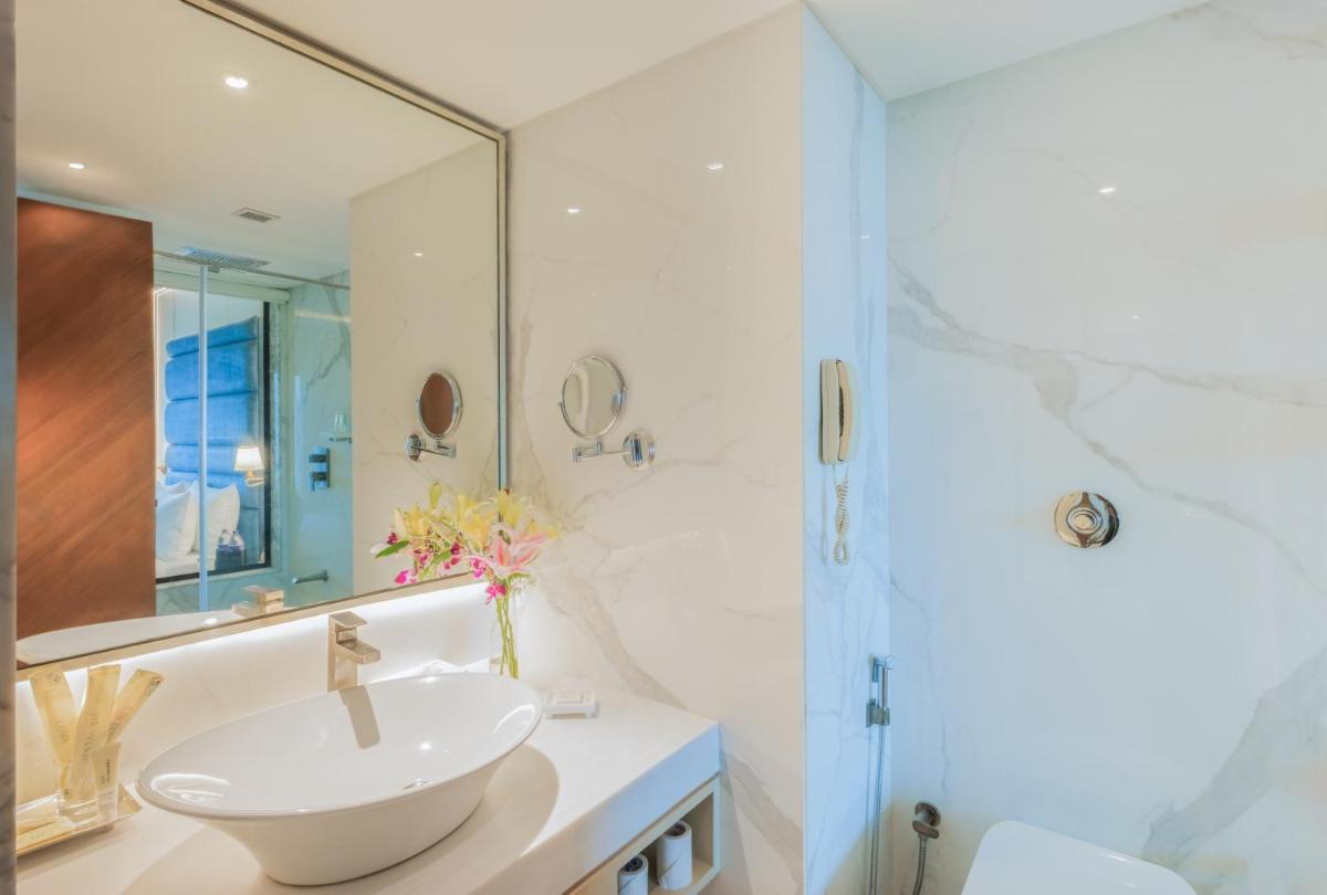 a white bathroom with a sink and a shower at Sayaji Pune in Pune