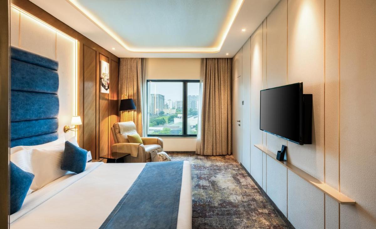 a hotel room with a bed and a flat screen tv at Sayaji Pune in Pune