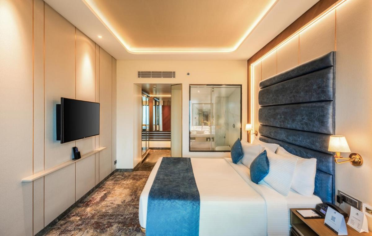 a hotel room with a bed and a flat screen tv at Sayaji Pune in Pune
