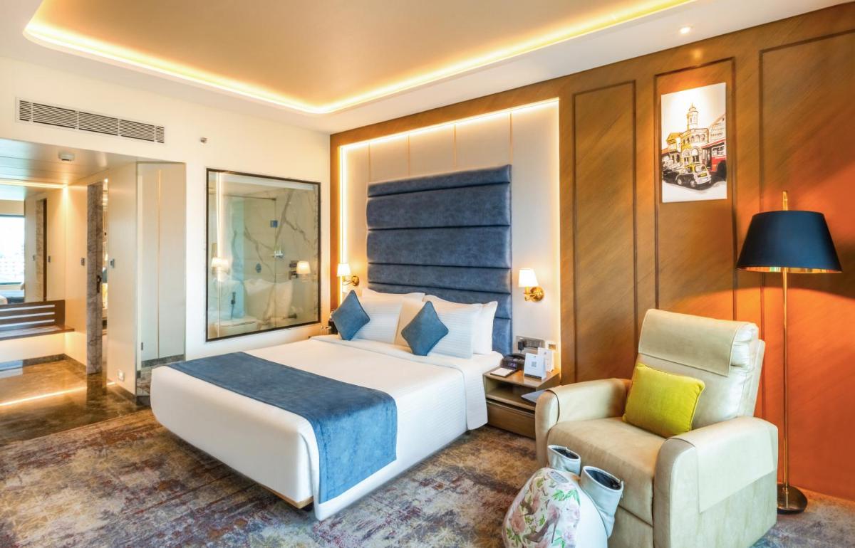 a hotel room with a bed and a chair at Sayaji Pune in Pune