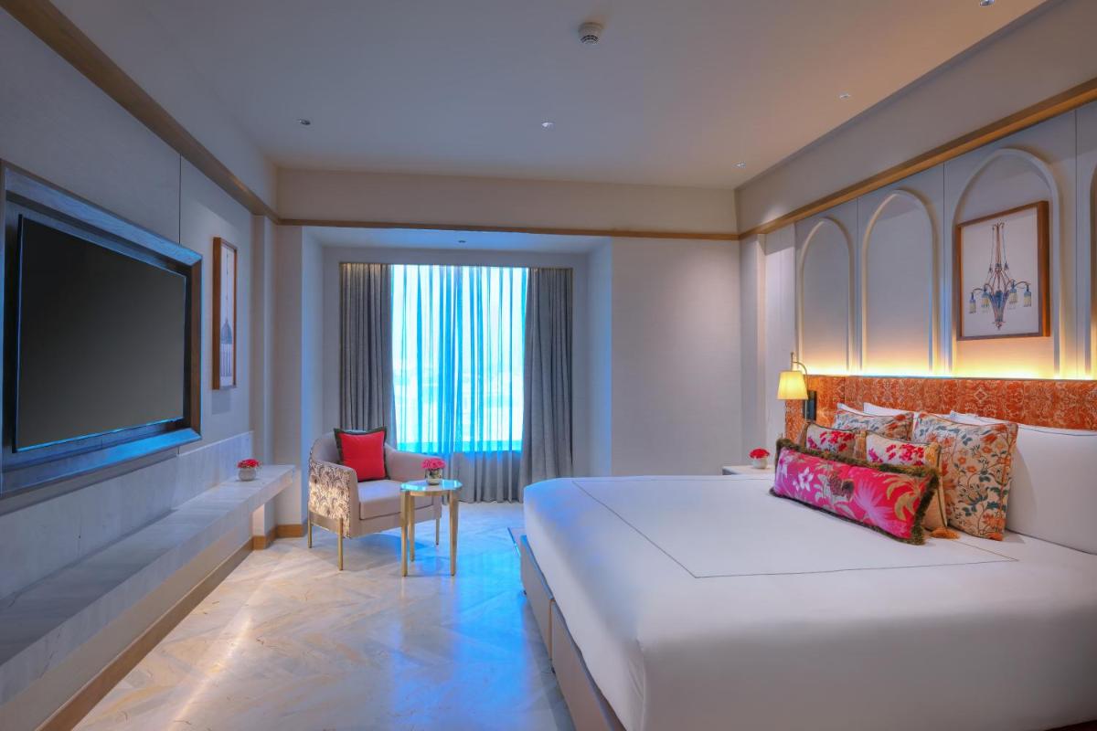 a hotel room with a large bed and a television at Taj Agra in Agra