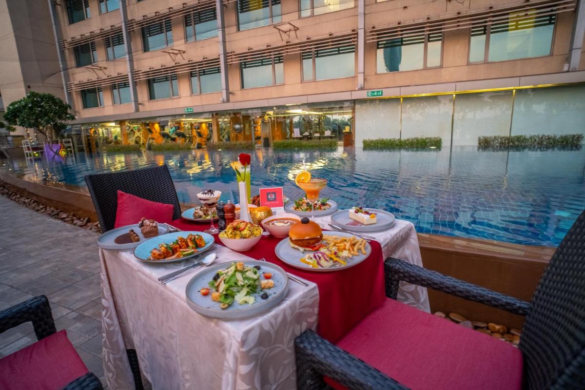 a table with plates of food in front of a pool at Crowne Plaza Ahmedabad City Centre by IHG in Ahmedabad