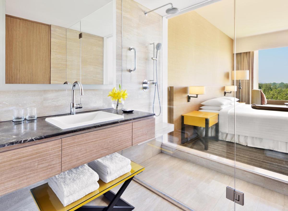 a bathroom with a sink and a bed at Courtyard by Marriott Bengaluru Outer Ring Road in Bengaluru