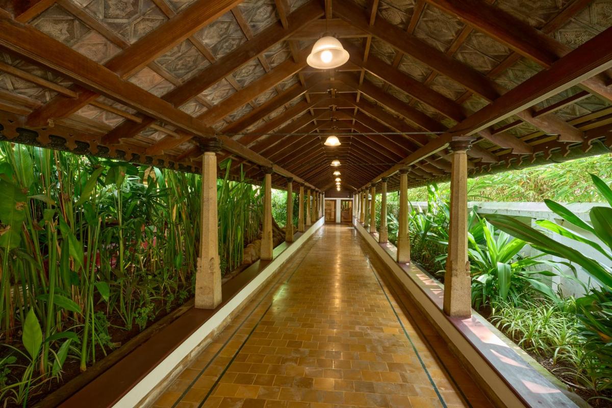 a walkway in a conservatory with plants at Casino Hotel - CGH Earth, Cochin in Cochin
